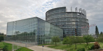 Здание Европарламента в Страсбурге со стеклянными фасадами и флагами