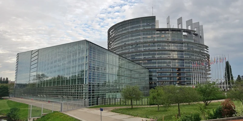 Здание Европарламента в Страсбурге со стеклянными фасадами и флагами